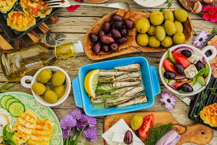 Грецький сніданок з оливками, сиром фета, рибою та салатом на столі
