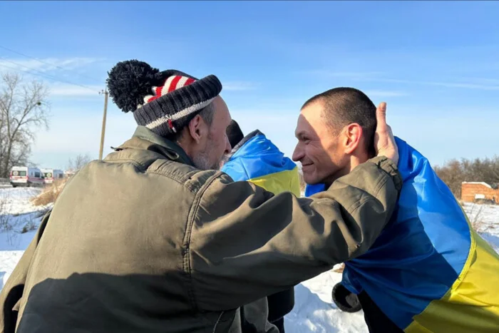 Батько і син, звільнені з полону, обіймаються під прапором України