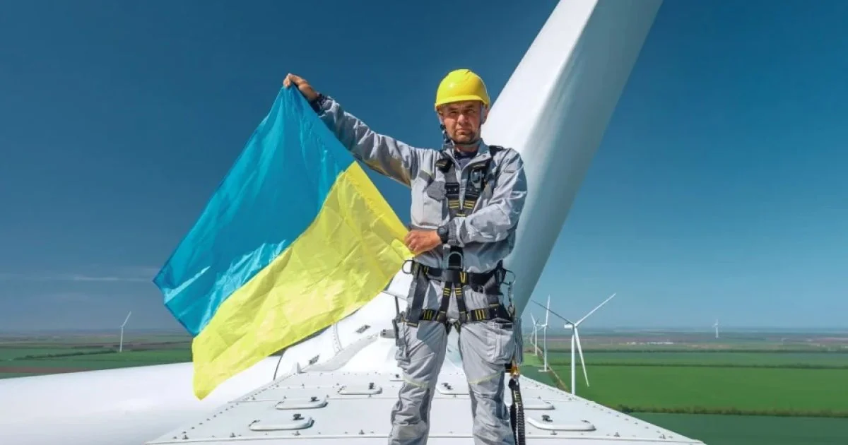 Працівник ДТЕК з прапором України на вітровій турбіні
