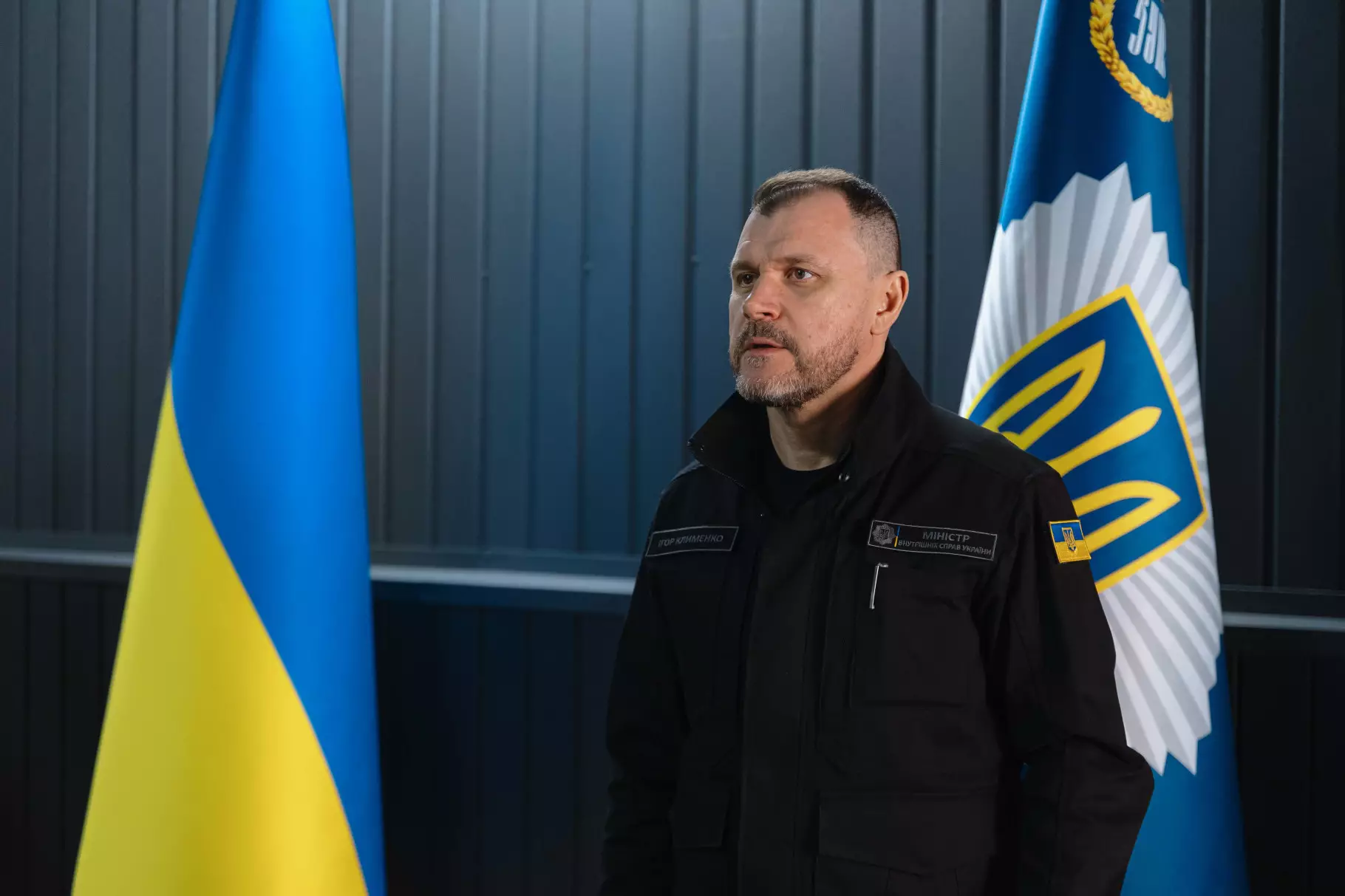 Ігор Клименко на тлі прапора України та емблеми МВС