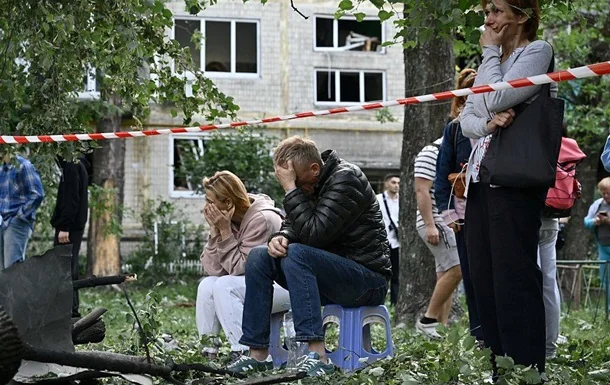 Люди в жалобі біля пошкодженої будівлі після атаки РФ у Києві