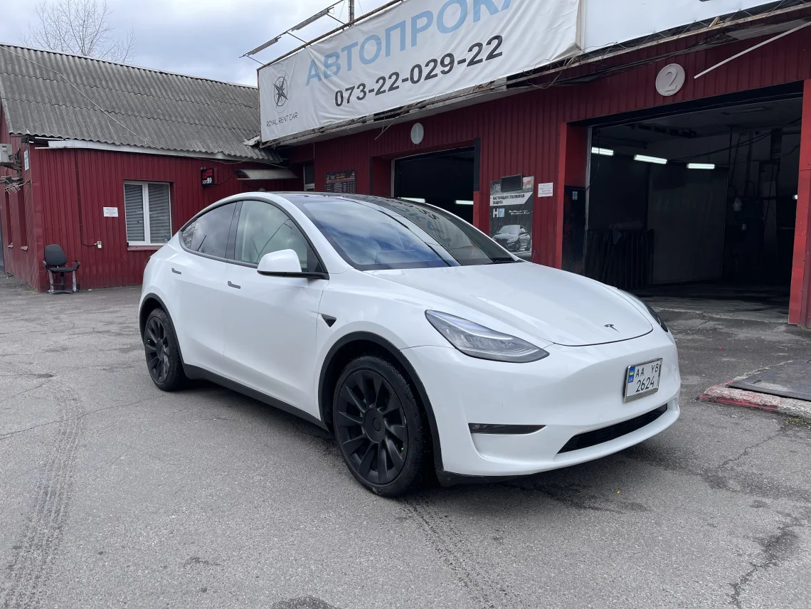 Біла Tesla Model Y перед автосервісом після повернення з оренди з пошкодженнями