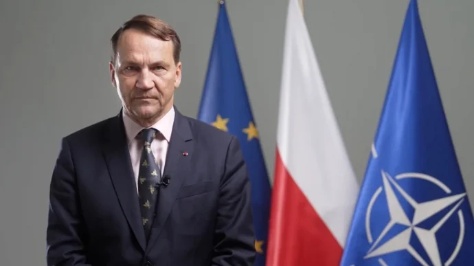 Міністр закордонних справ Польщі Радослав Сікорський на тлі прапорів ЄС, Польщі та НАТО