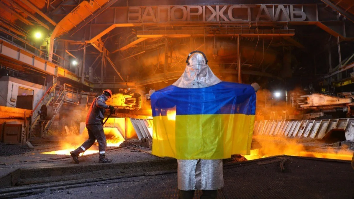 Працівник Запоріжсталі тримає прапор України в гарячому цеху