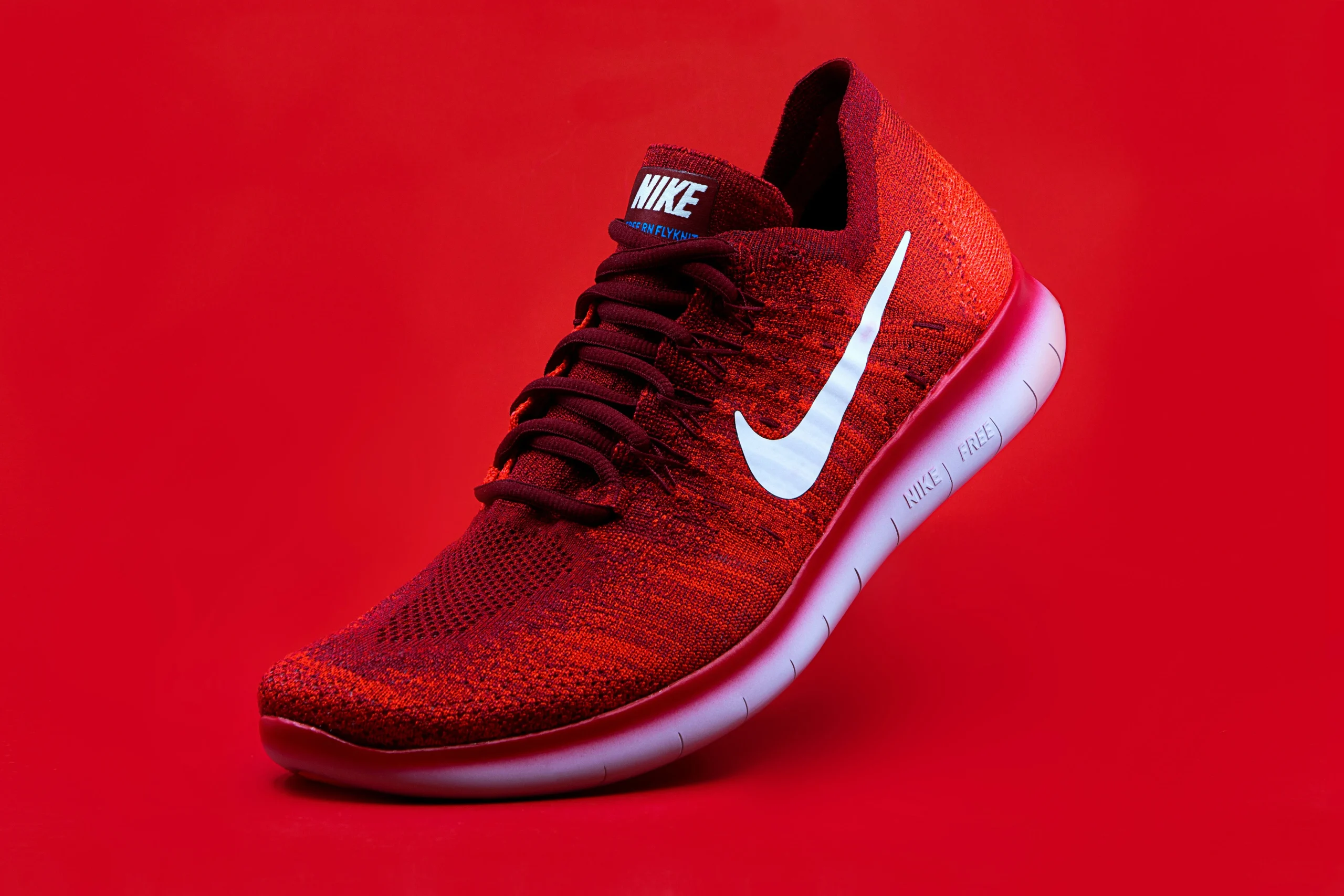 Яскраво-червоні кросівки Nike Free RN Flyknit з білою підошвою на червоному тлі